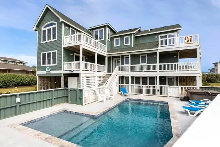 Pool with a tile waterline and pale coping behind an Outer Banks beach house