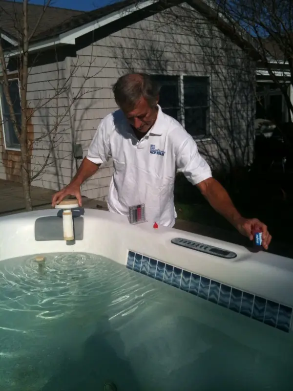 Technician reading a water test strip beside a spa